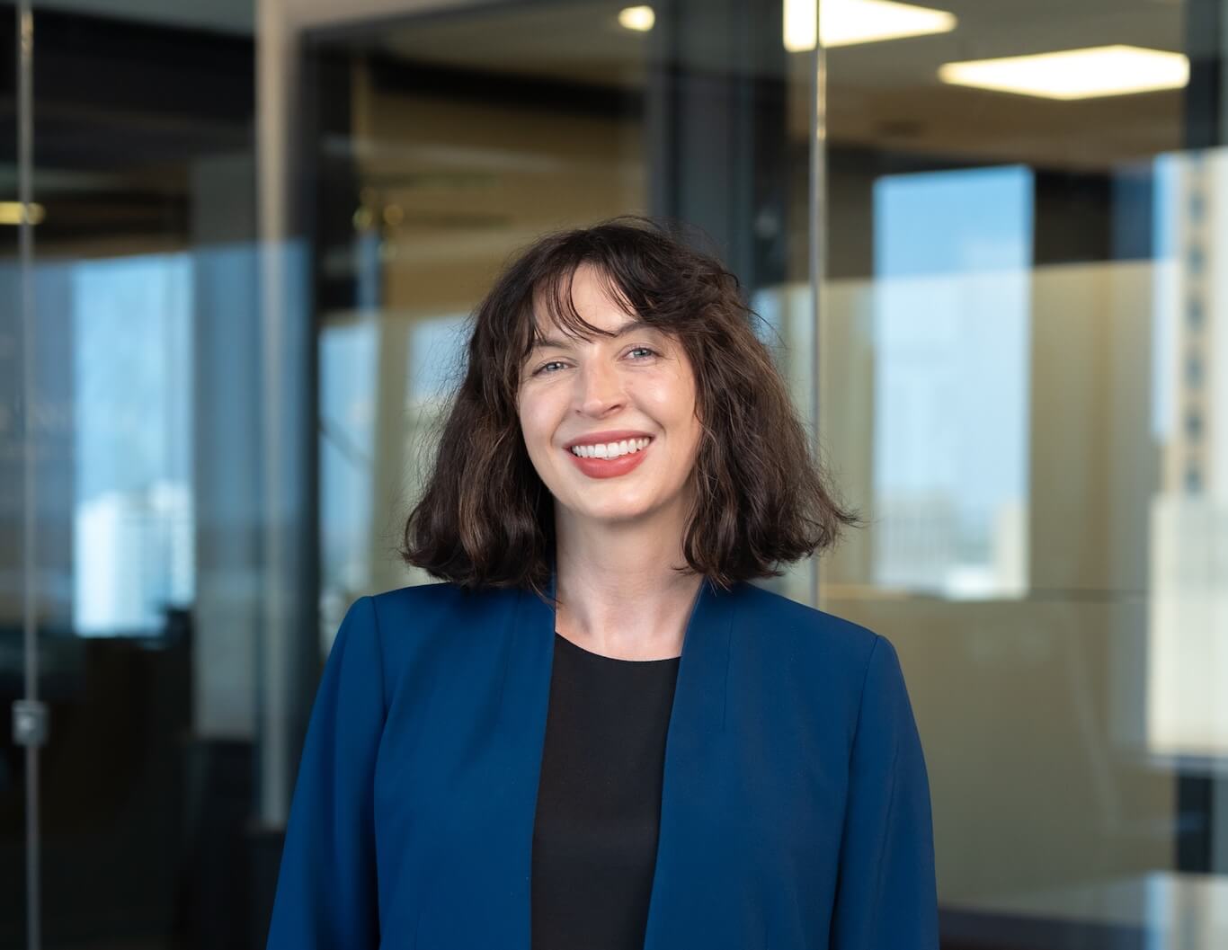 Kylie Shelley smiling in front of office glass windows